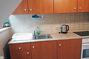 Küchenzeile mit 4-Platten-Cerankochfeld, Ofen, Wasserkocher und Spüle.