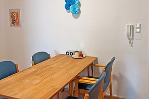 Holztisch mit 4 Stühlen an einer Wand 
