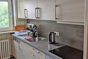 Küchenzeile mit 4-Platten-Cerankochfeld, Wasserkocher, Spülmaschine und Besteck.