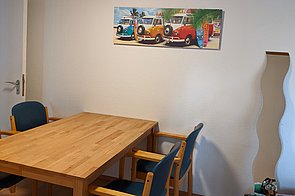 Holztisch mit 4 Stühlen an einer Wand.
